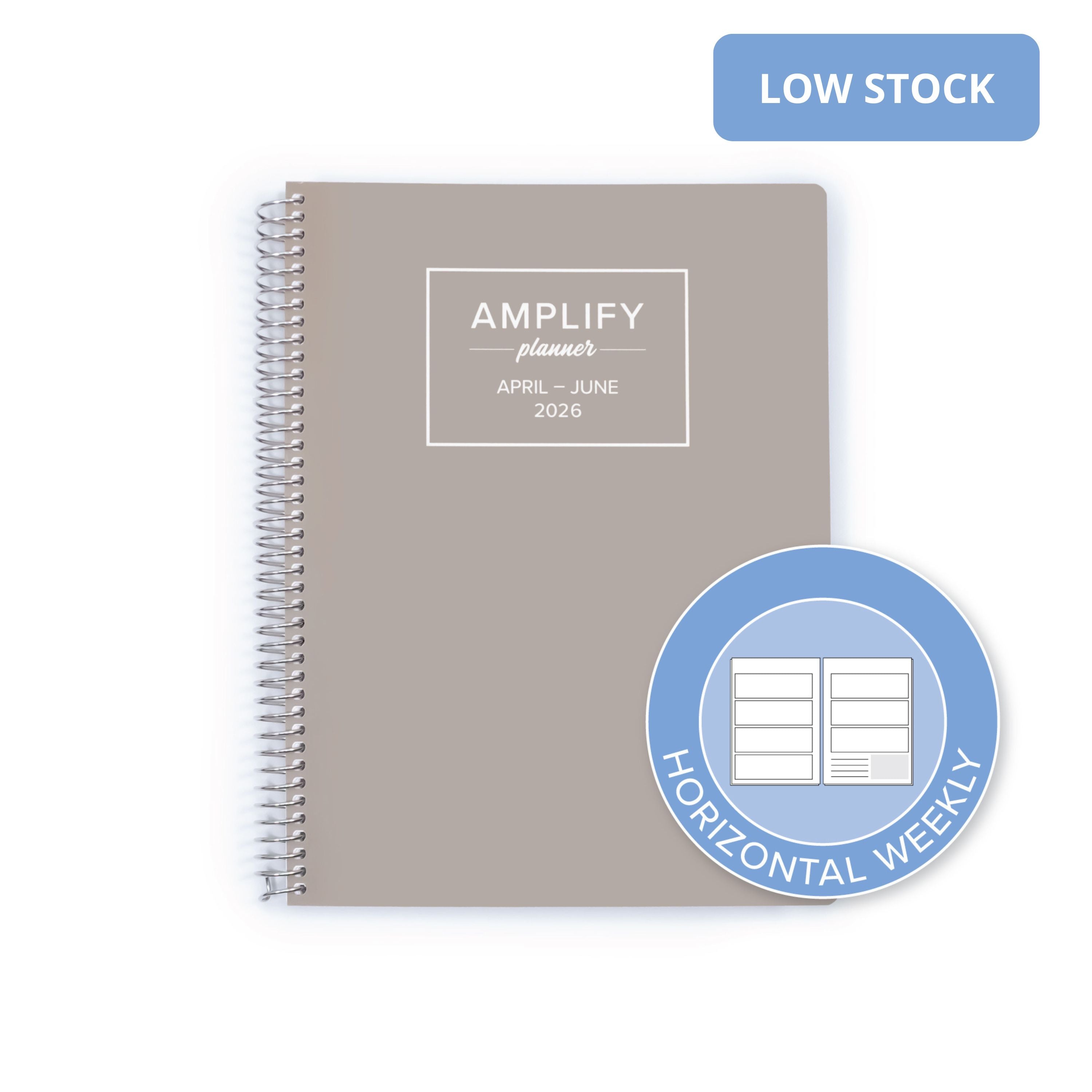 A taupe gray spiral-bound planner shown on a white background, with a blue 'LOW STOCK' banner in the top right and a blue circular badge in the bottom right reading 'HORIZONTAL WEEKLY'. The planner cover has a white printed label that reads 'AMPLIFY planner APRIL - JUNE 2026'.