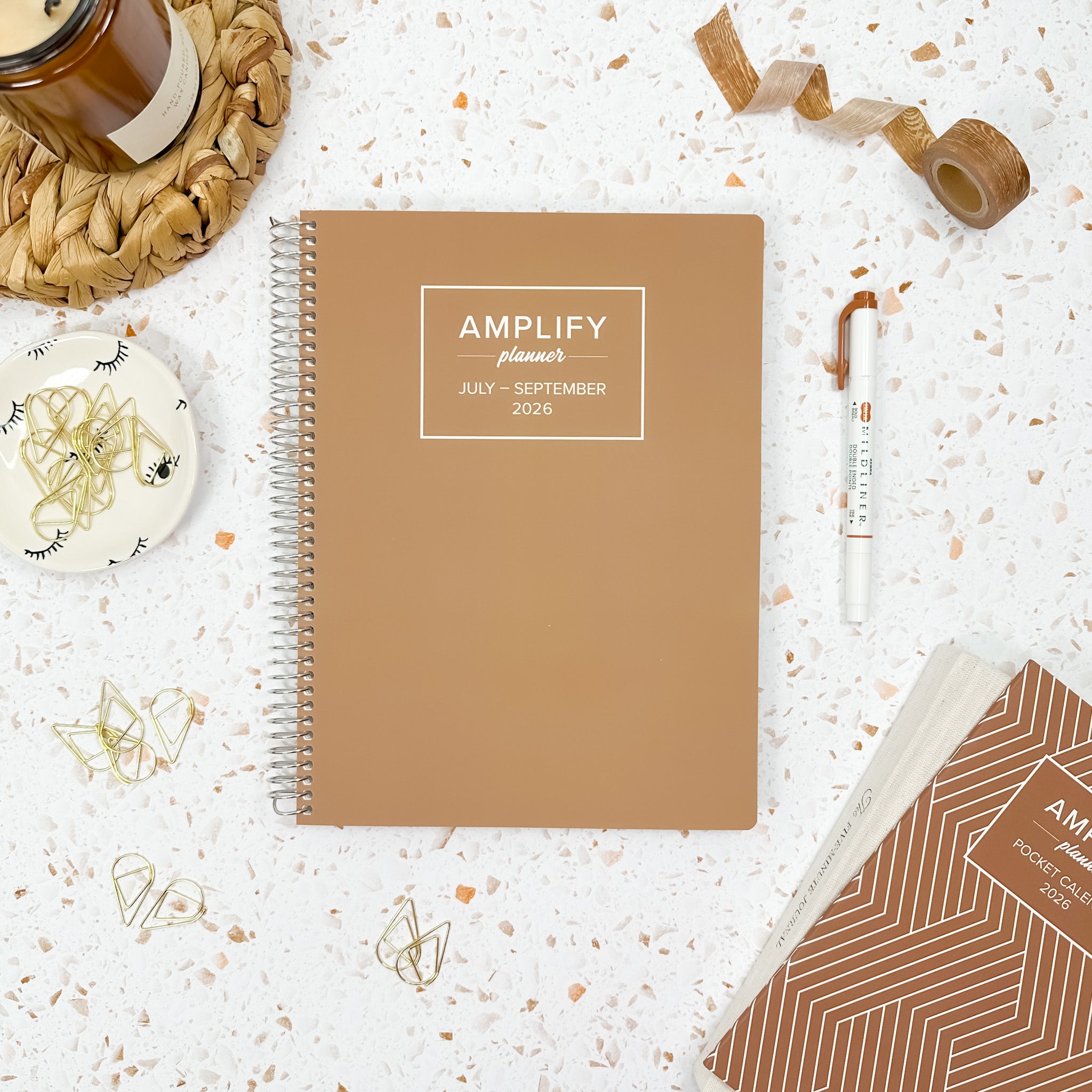 Daily Planner - July-September 2026 displayed with accessories on a textured surface, showcasing the Nomad Brown design by Amplify Planner.