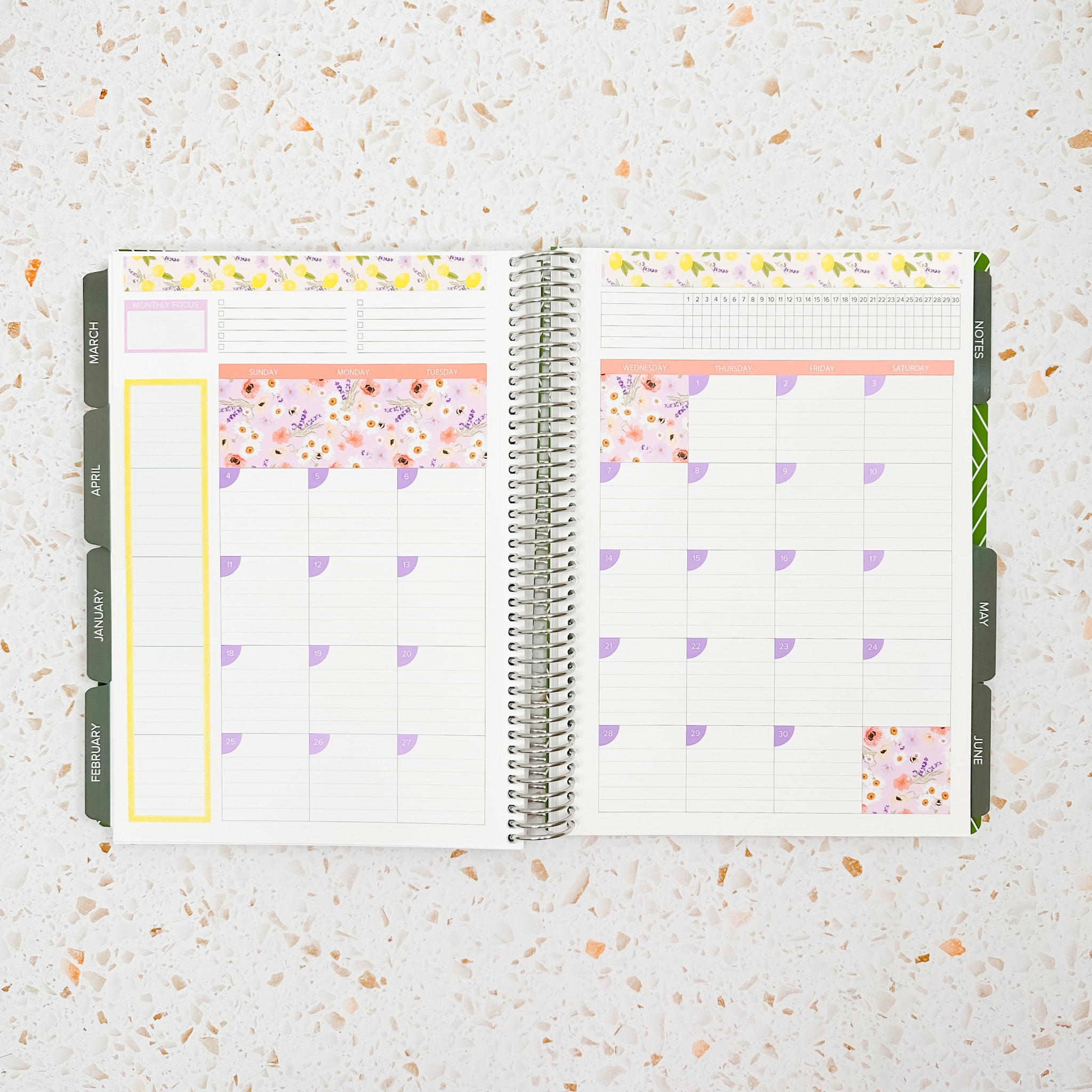 Open monthly planner spread decorated with the Lavender & Honey Monthly Sticker Kit featuring pastel floral stickers, lavender accents, soft peach tones, and lemon-patterned borders.