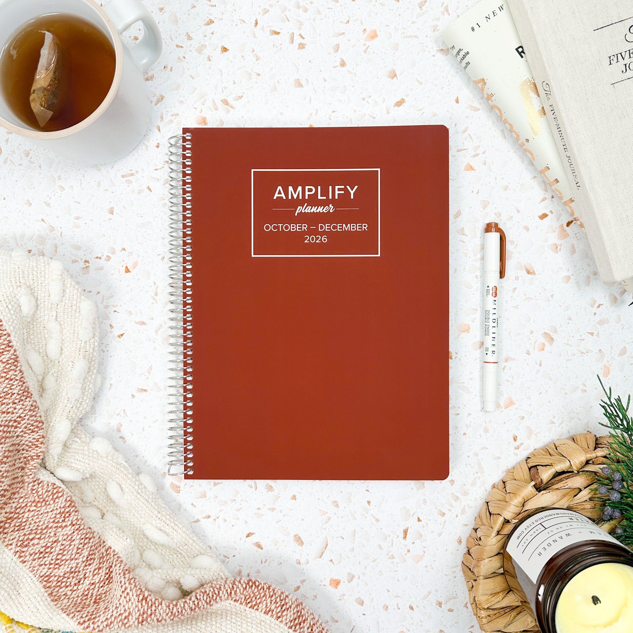 Daily Planner - October-December 2026 - Amplify Planner displayed on a desk with creative tools, showcasing its stylish tan cover.