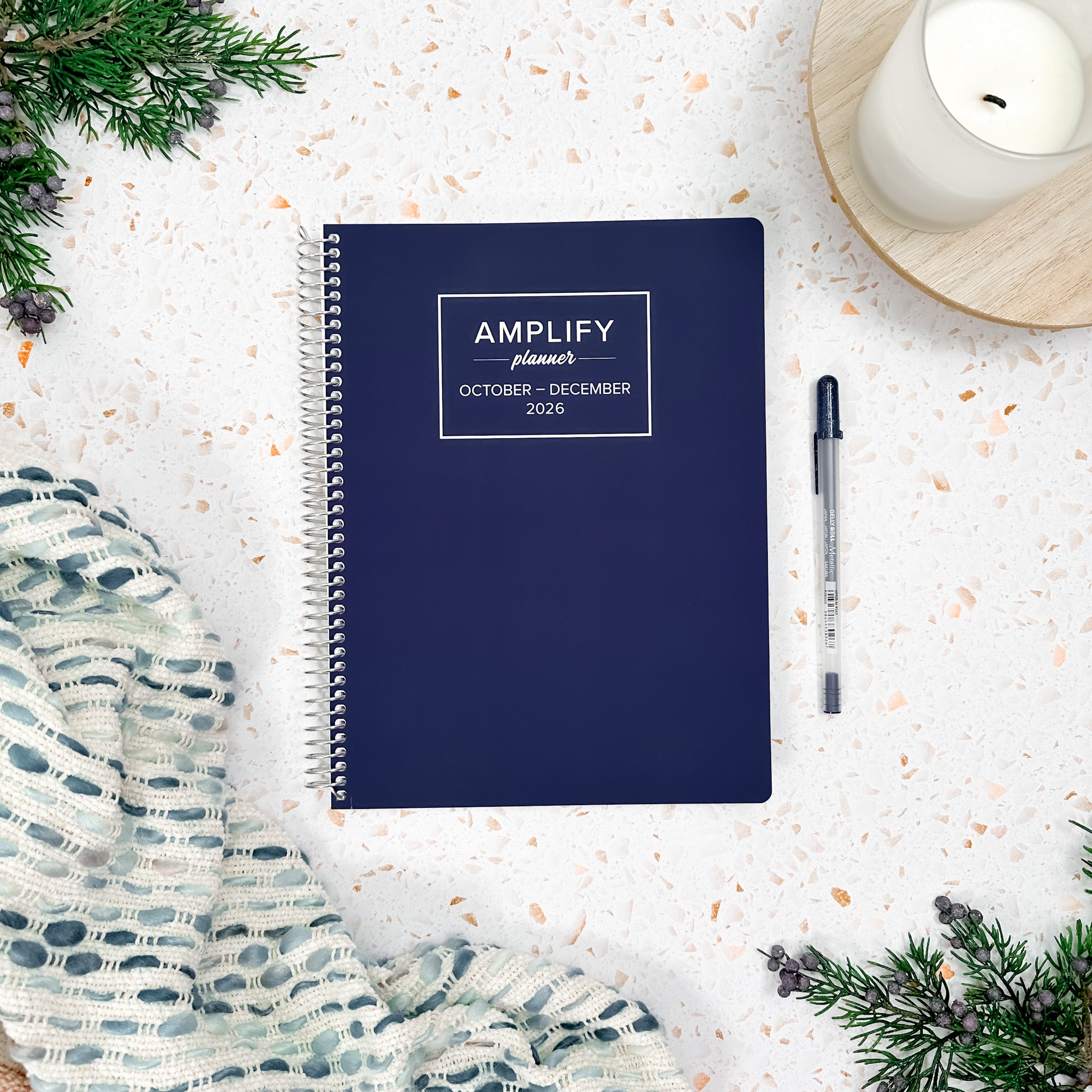 Daily Planner - October-December 2026 - Amplify Planner displayed on a desk with creative tools, showcasing its stylish blue cover.