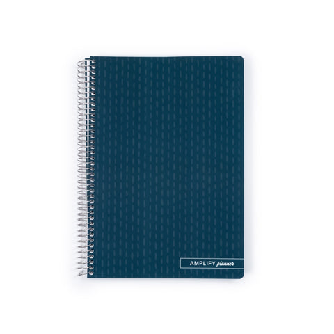 A dark teal spiral-bound planner with a subtle geometric pattern on the cover, featuring a silver wire binding and a small white label at the bottom right that reads 'AMPLIFY planner'.