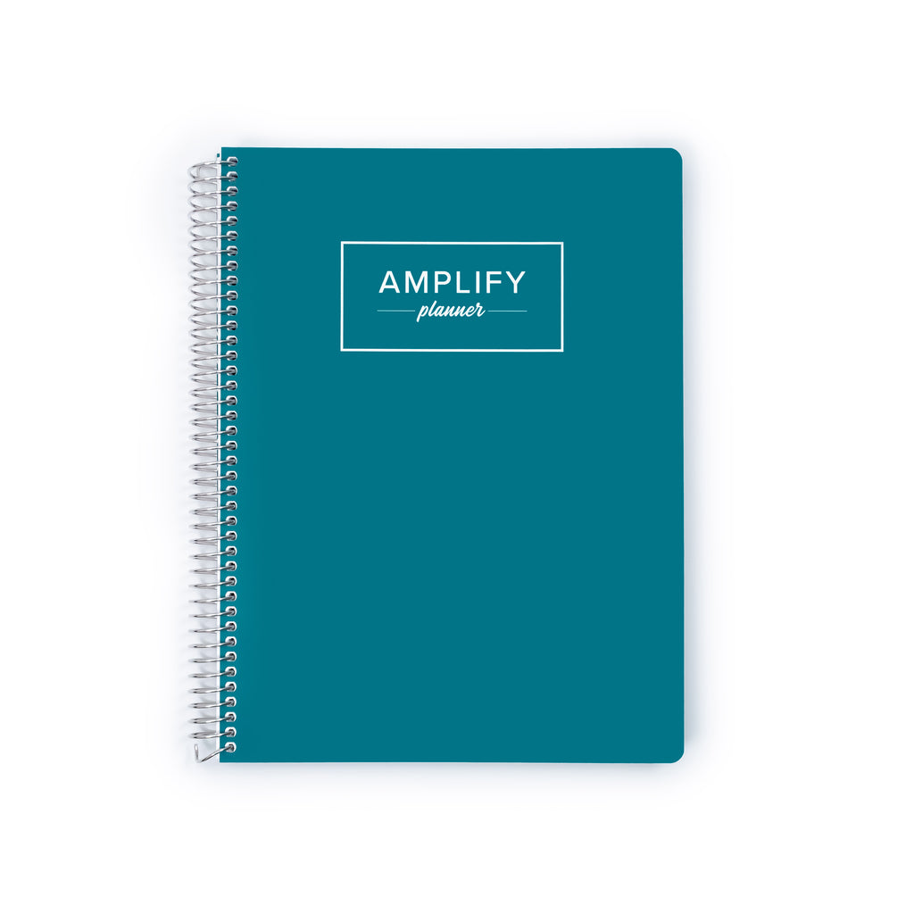A teal spiral-bound planner with a white wire binding and a white rectangular logo on the front that reads 'AMPLIFY planner'.